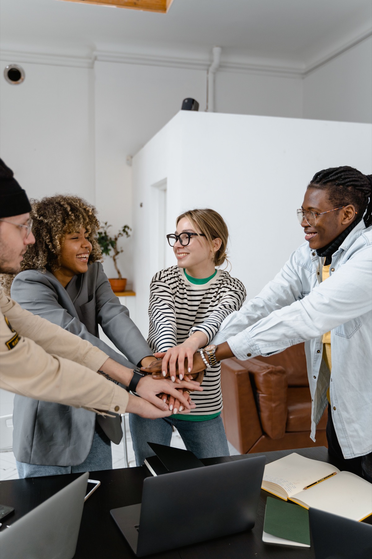 A small group collaborating and joining hands around a table